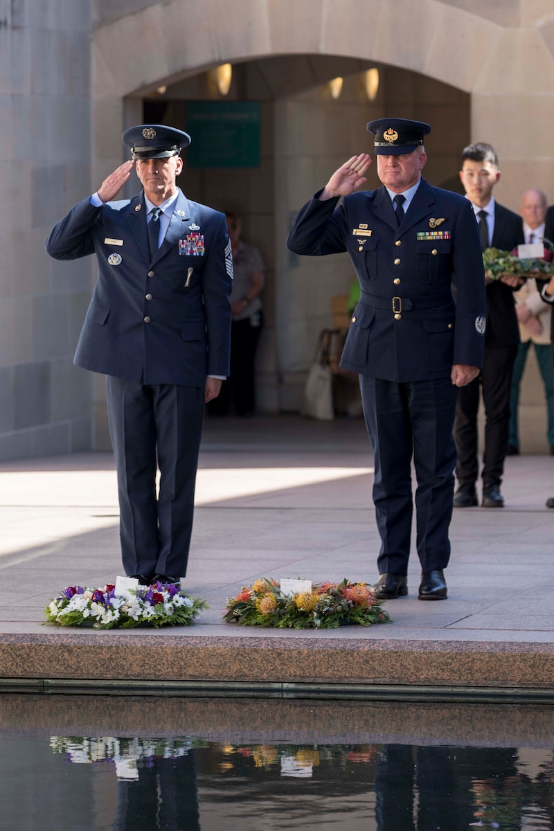 Military members salute wreaths.